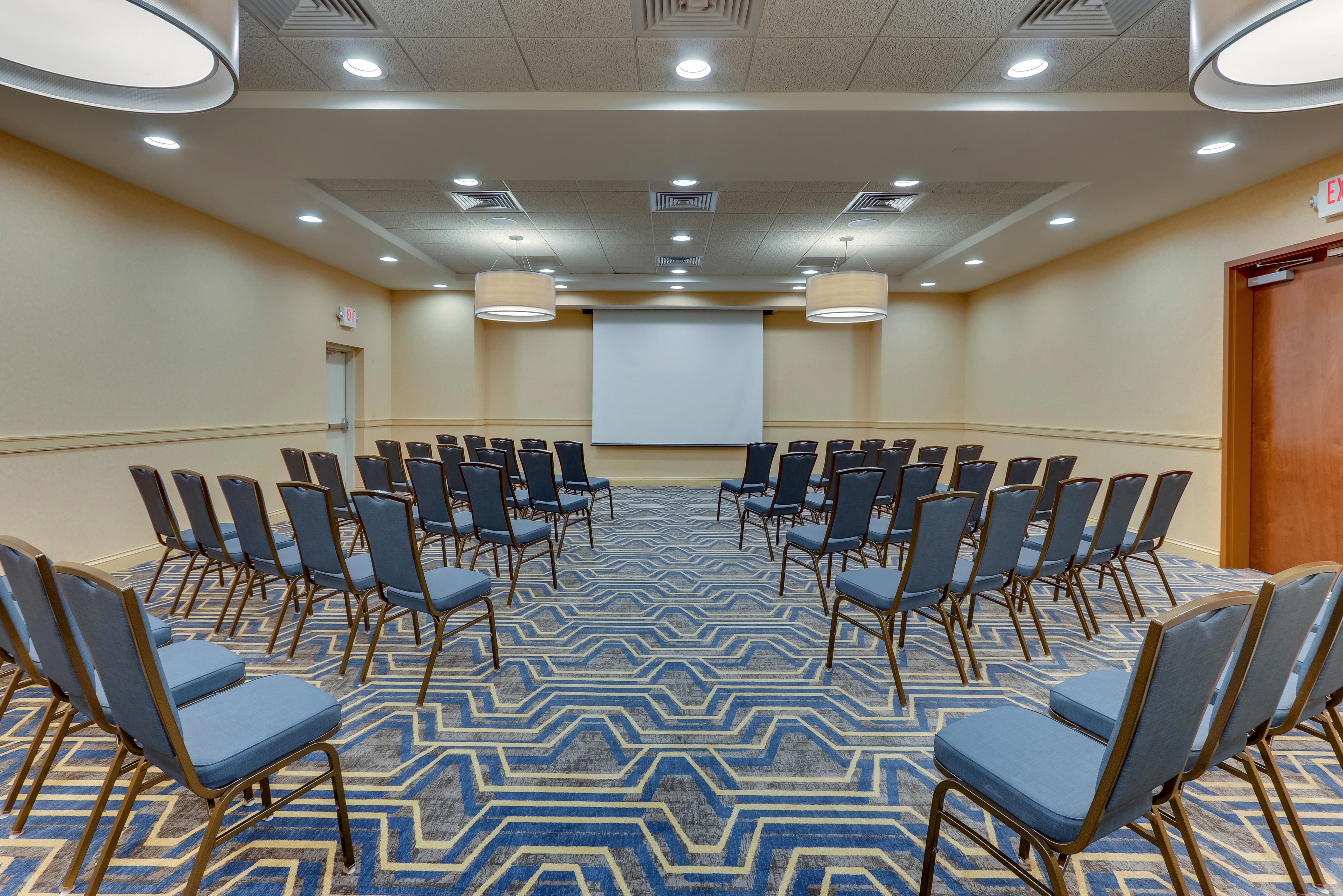 Meeting space set up with only chairs and a projector screen